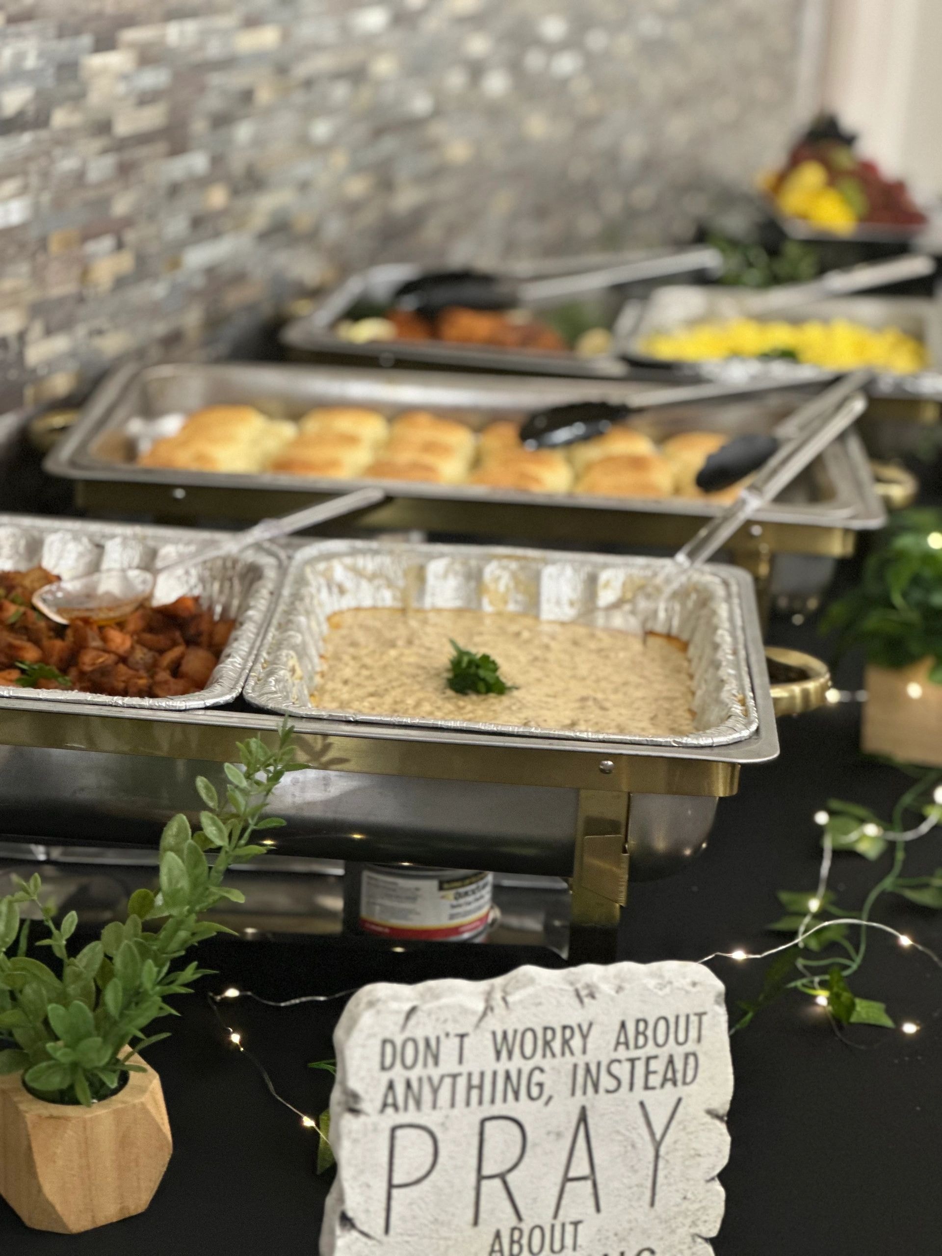 Catered buffet display with rolls, hummus and sides in chafing dishes